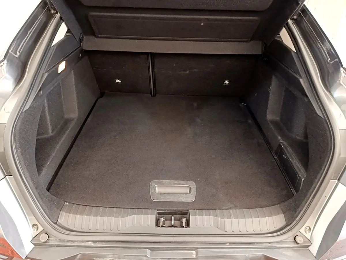 Coffre ouvert vu de l'arrière d'une Renault Arkana gris clair, espace de chargement propre et spacieux.