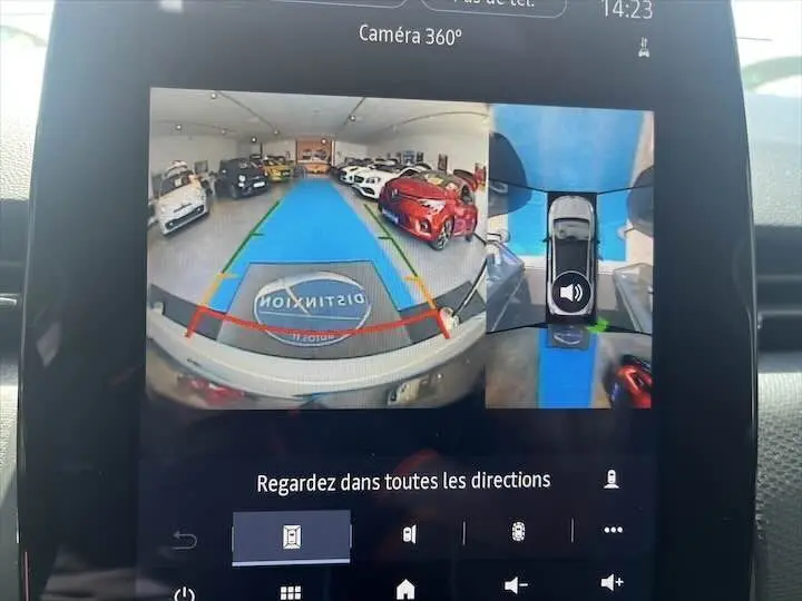 Vue écran caméra 360° montrant l'arrière d'une Renault Clio V blanc nacré dans un showroom avec plusieurs voitures.