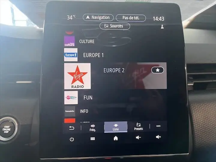 Écran tactile central de la Renault Clio V blanc nacré, affichant les options radio et navigation en intérieur.