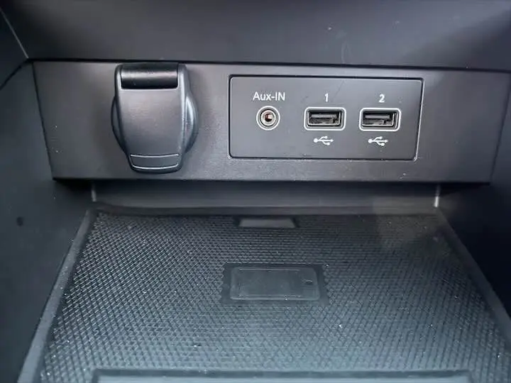 Prise auxiliaire et deux ports USB noirs dans la console centrale d'une Renault Clio V blanche nacrée.