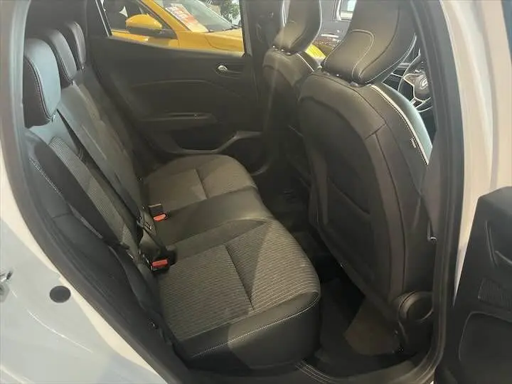 Vue intérieure arrière de la Renault Clio V blanc nacré, sièges arrière en tissu gris et cuir noir avec surpiqûres blanches.