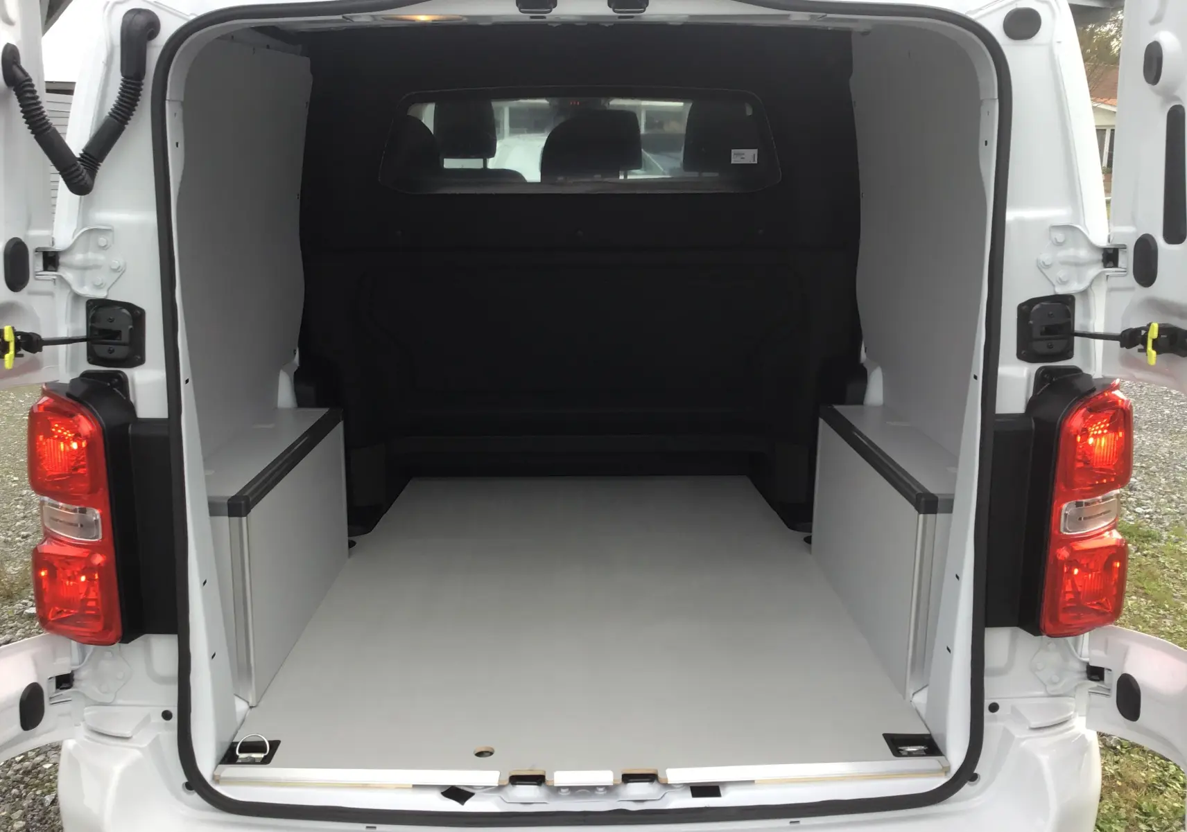 Vue arrière du Citroën Jumpy blanc avec portes ouvertes, montrant l'espace de chargement vide et aménagé.