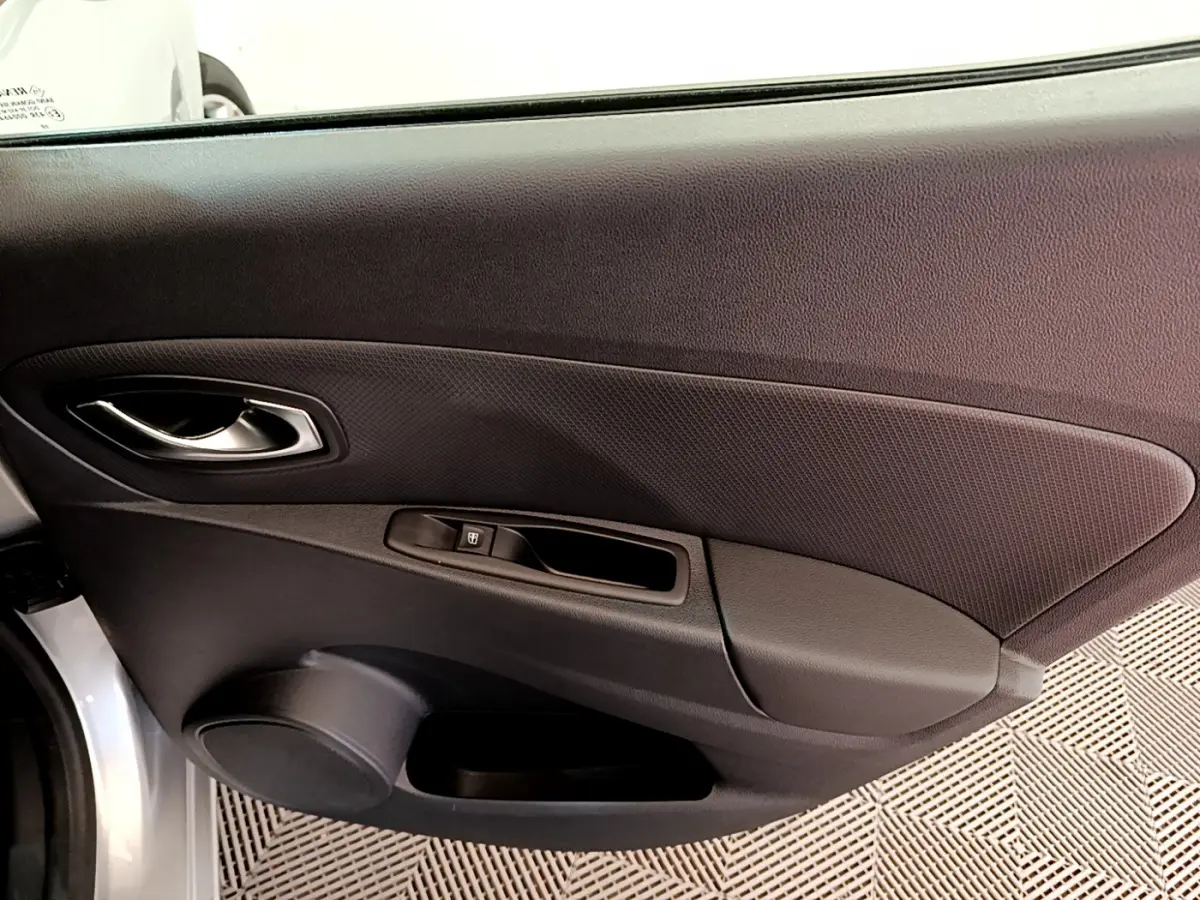 Gros plan sur la porte côté gauche d'une Renault Clio Business gris clair, avec poignée argentée et commande de vitre électrique.