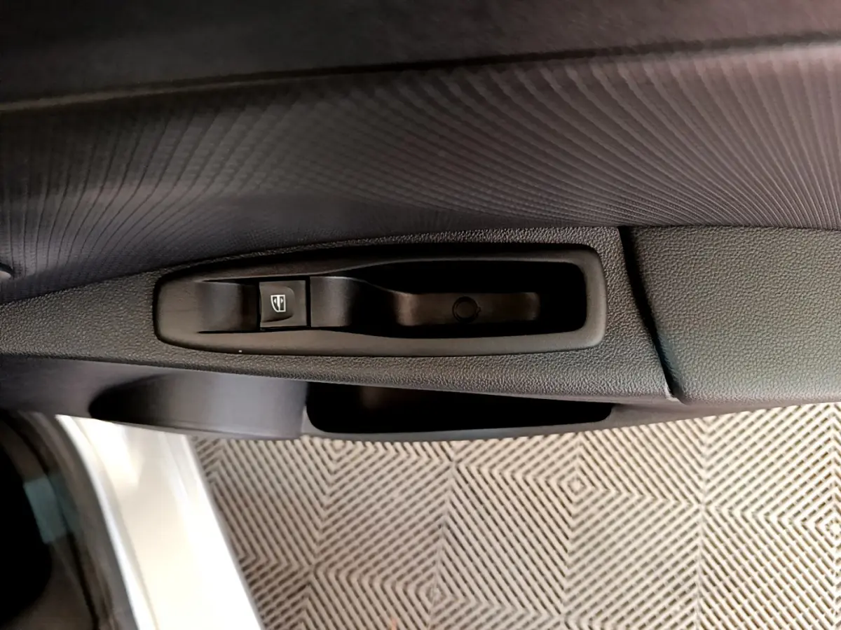 Gros plan sur la commande de lève-vitre côté conducteur de la Renault Clio Business TCe 90 gris clair de 2019.