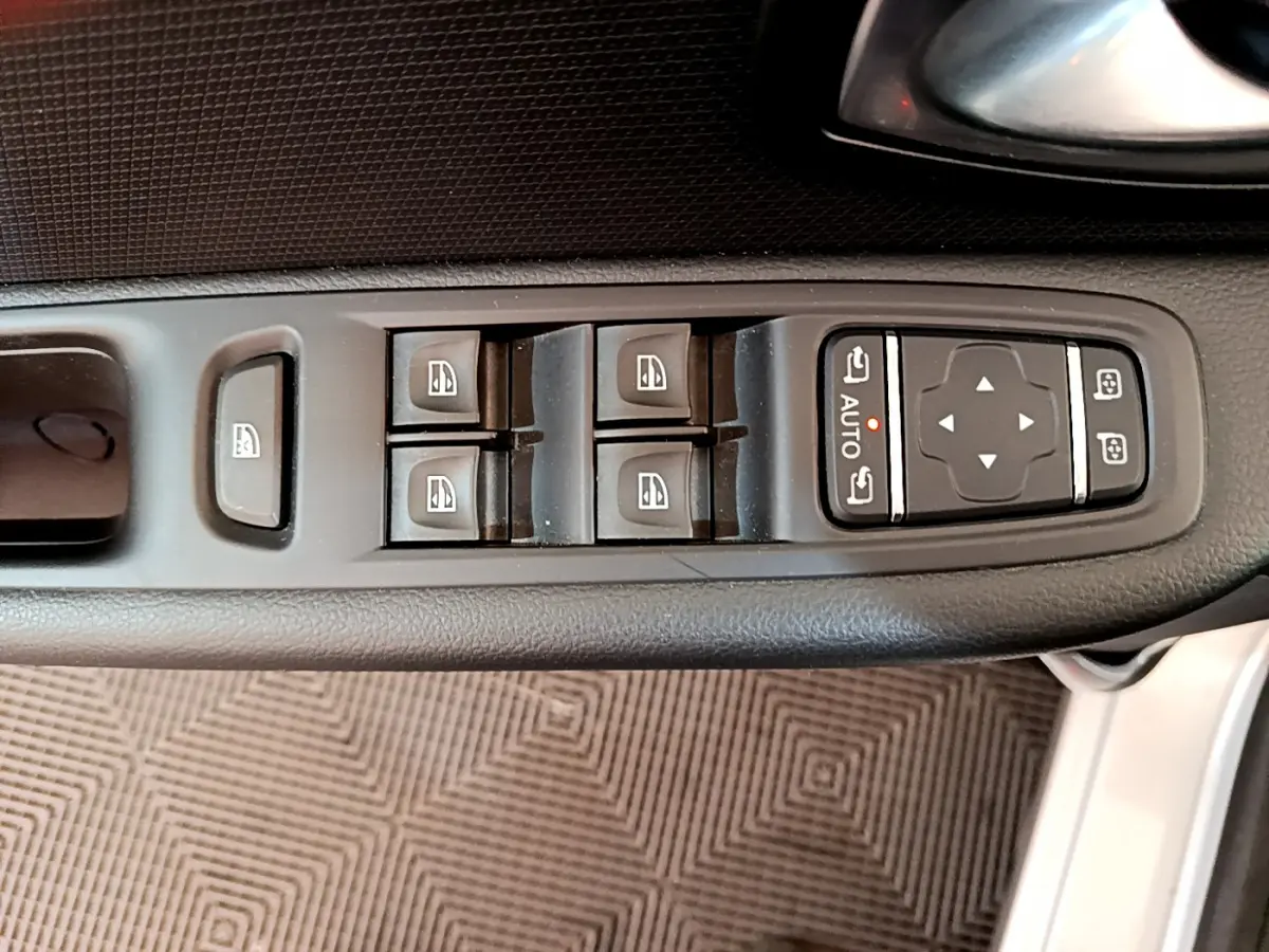 Gros plan sur les commandes des vitres et rétroviseurs côté conducteur d'une Renault Clio Business gris clair de 2019.