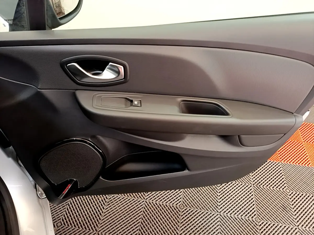 Vue intérieure côté gauche de la porte avant d'une Renault Clio Business gris clair avec haut-parleur intégré et poignée chromée.