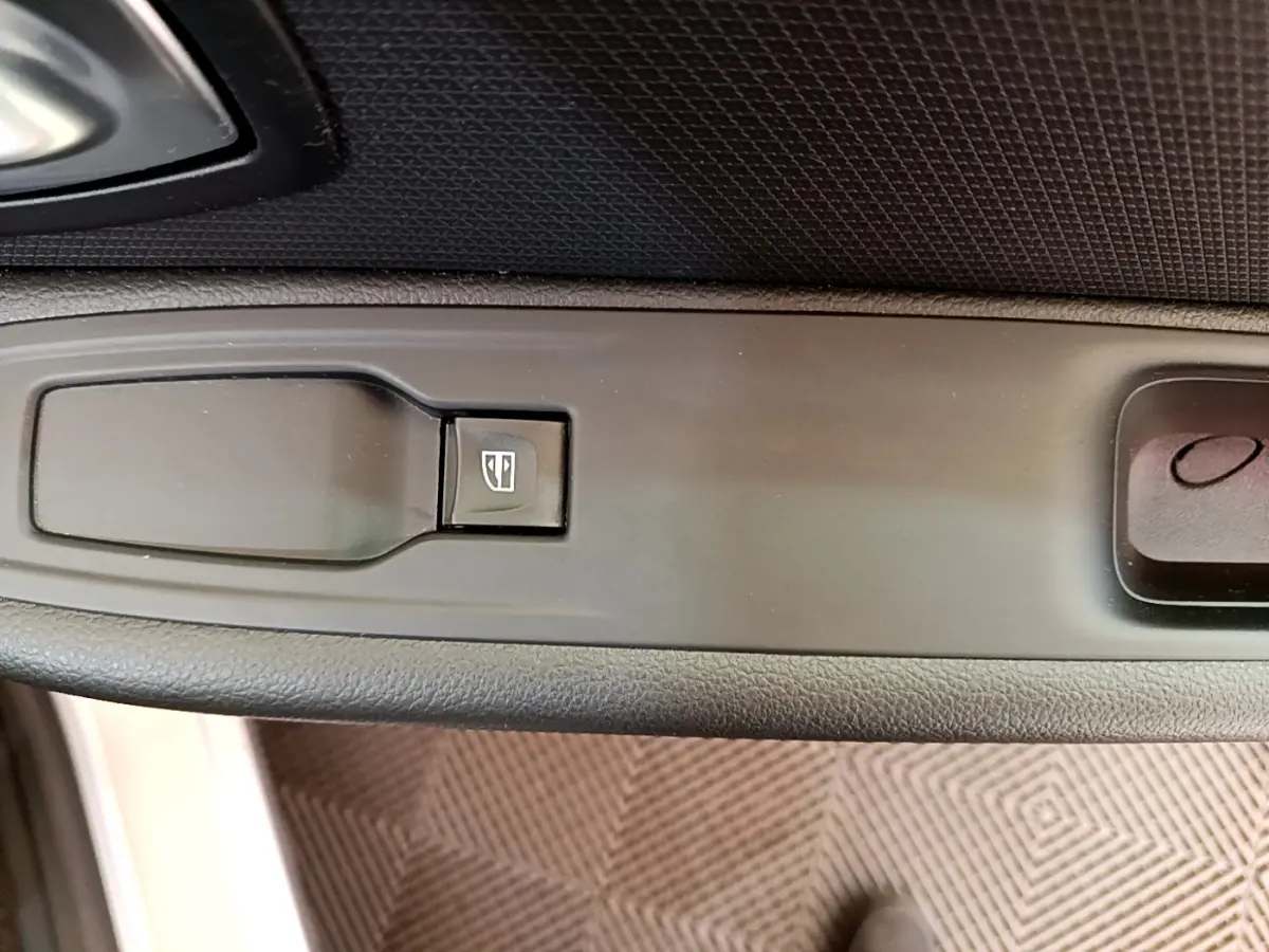 Gros plan sur la commande de lève-vitre côté conducteur d'une Renault Clio Business gris clair, intérieur noir.