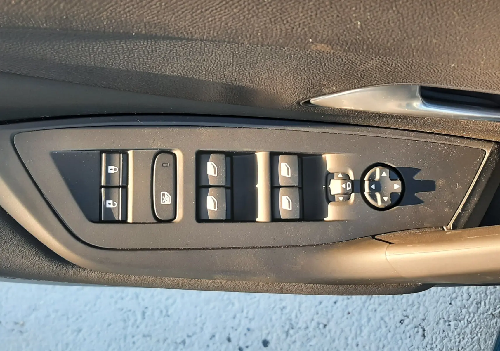 Panneau de commandes des vitres et rétroviseurs côté conducteur d'une Peugeot 308 Bleu Obsession, intérieur noir.