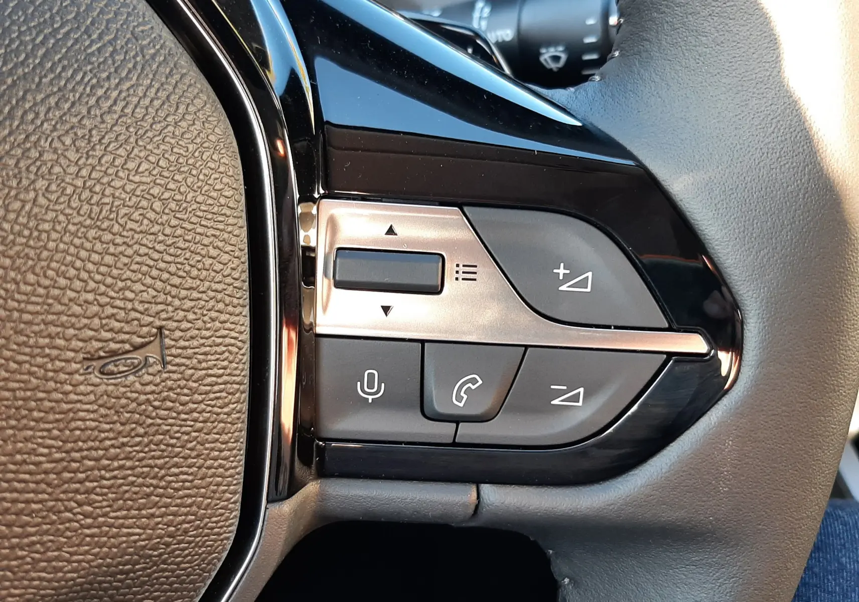 Gros plan sur les commandes du volant à droite d'une Peugeot 308 Bleu Obsession, boutons pour audio et téléphone.