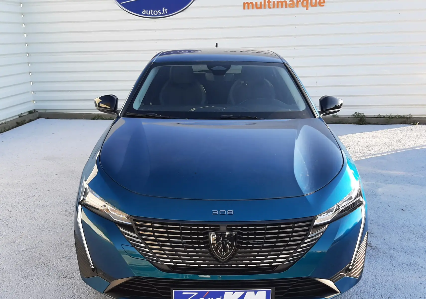 Vue frontale d'une Peugeot 308 Bleu Obsession 2025 avec calandre noire et logo lion bien visible.