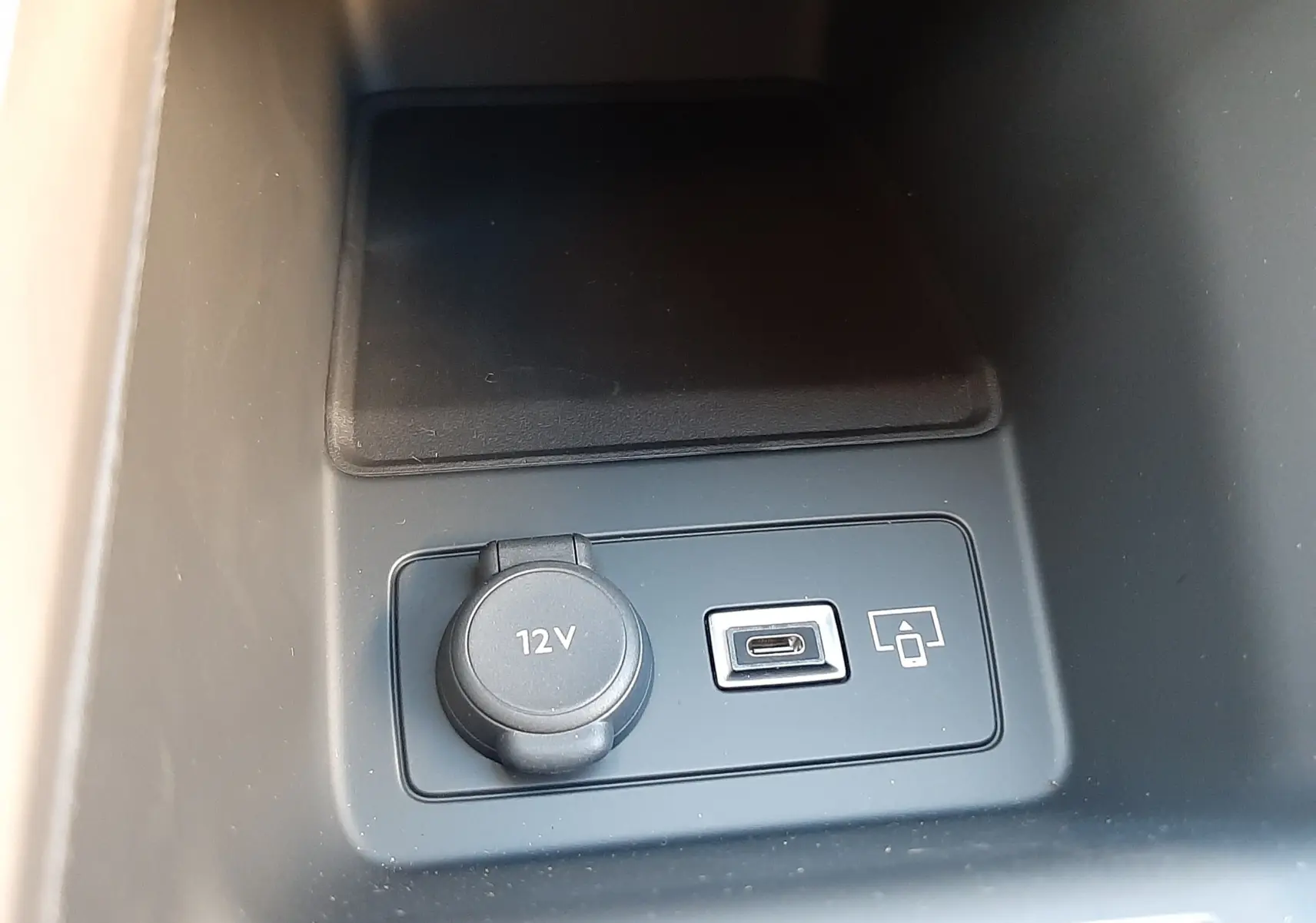 Prise 12V et port USB-C en gros plan dans la console centrale noire de la Peugeot 308 Bleu Obsession 2025.