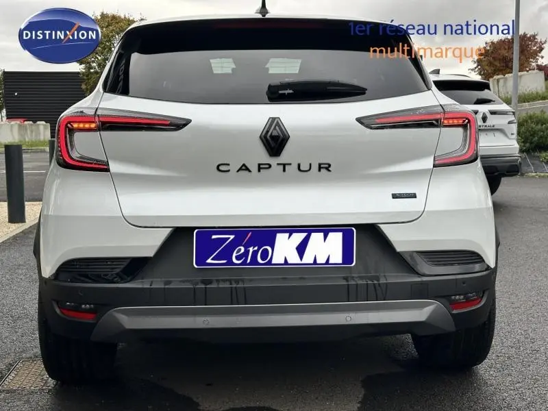 Vue arrière d'un Renault Captur 2025 blanc, version hybride esprit Alpine avec feux LED distinctifs et plaque Zéro KM.