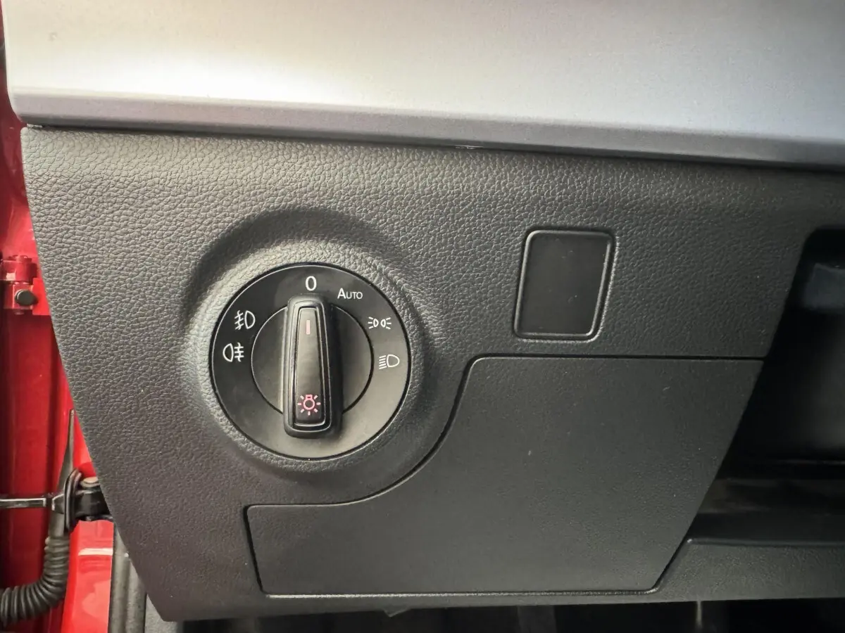 Gros plan sur le bouton de commande des phares dans l'habitacle d'une SEAT Ibiza rouge, côté conducteur.