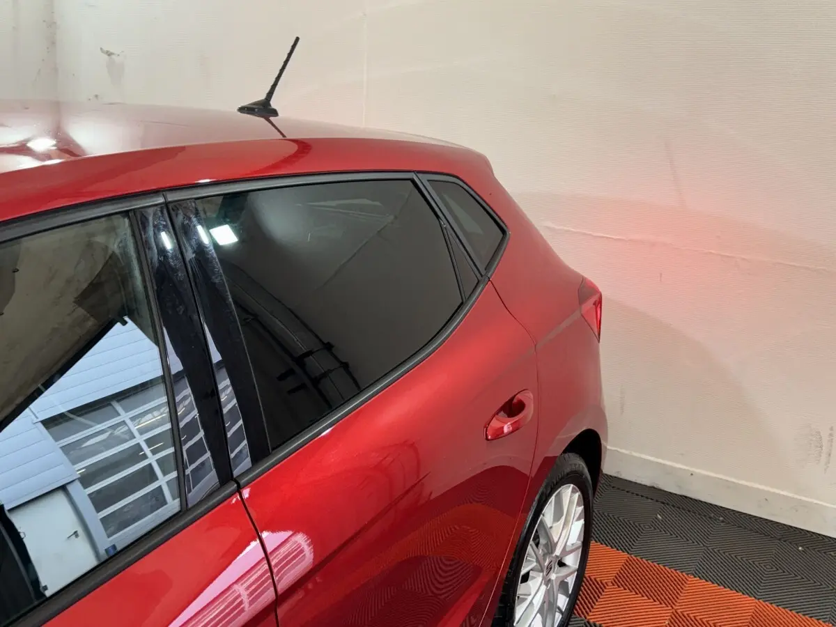 Vue 3/4 arrière droite d'une SEAT Ibiza 1.0 TSI 110 FR rouge avec vitres teintées et jantes alliage argentées.