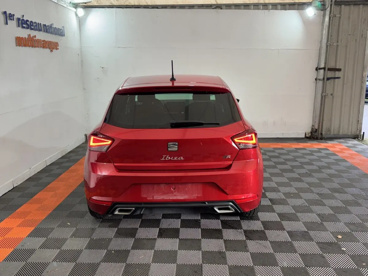 Vue arrière d'une SEAT Ibiza 1.0 TSI 110 FR rouge avec feux LED triangulaires et double sortie d'échappement chromée.
