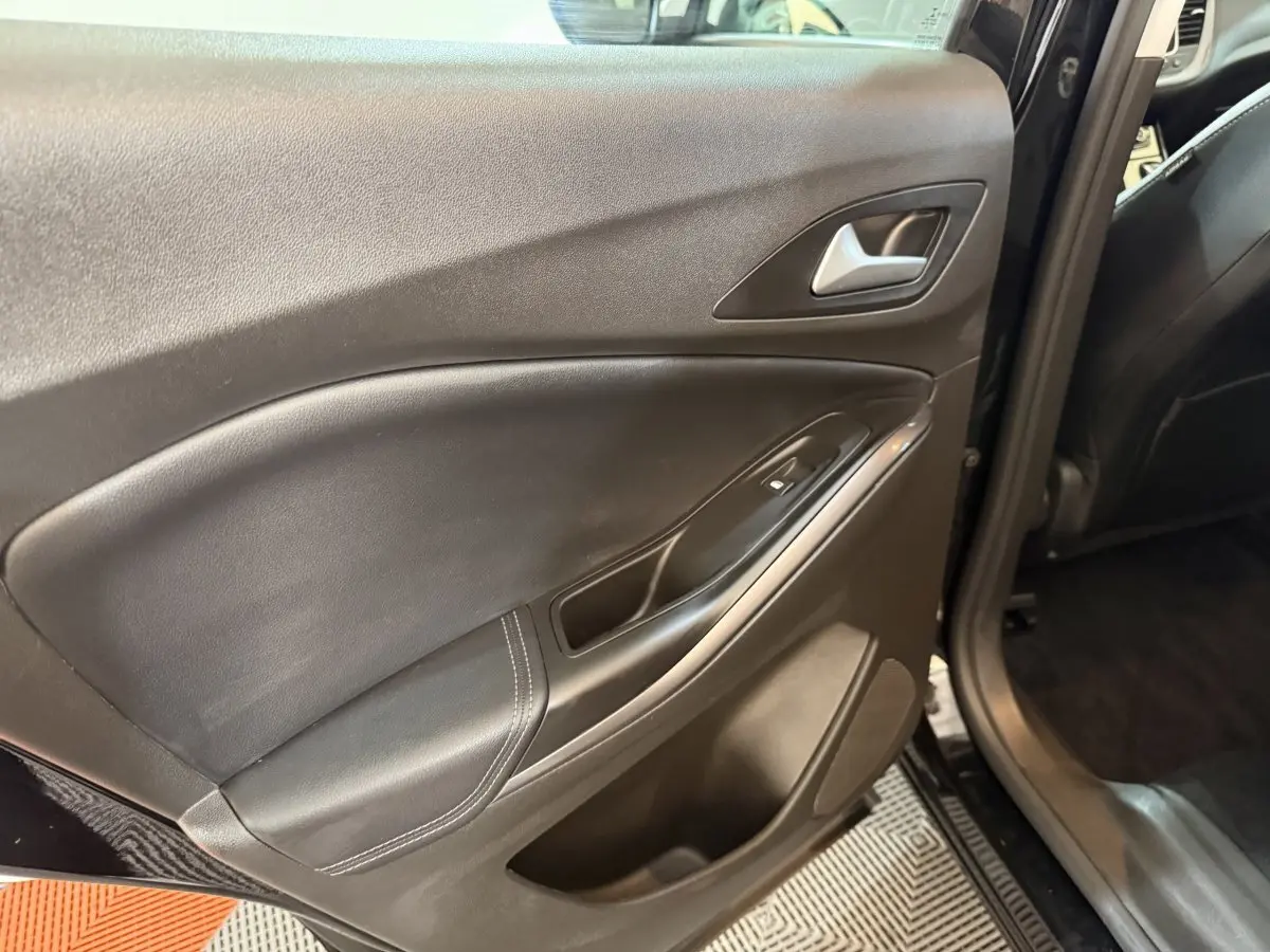 Vue intérieure sur la porte arrière gauche noire de l’Opel Grandland X avec poignée et commande de vitre électrique.