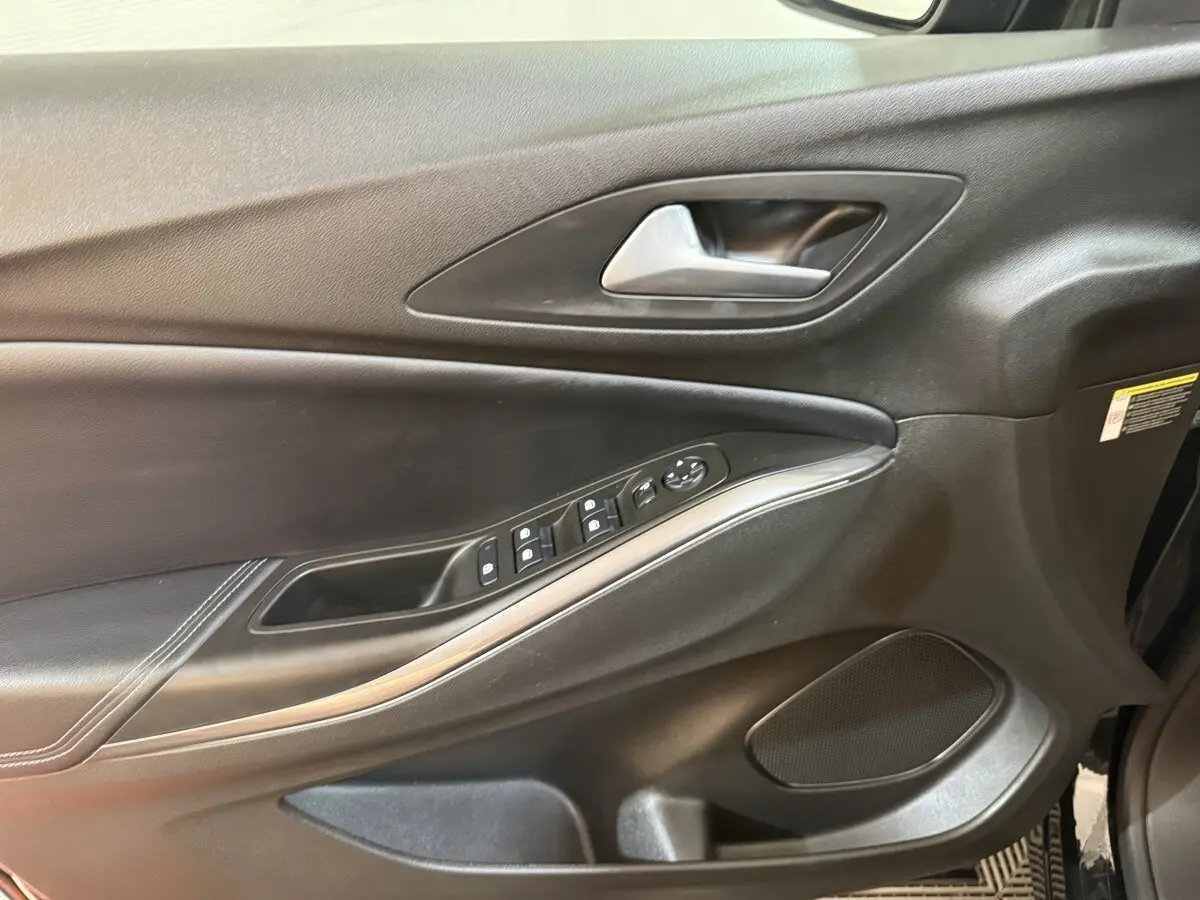 Vue intérieure du panneau de porte côté conducteur noir de l'Opel Grandland X 2021 avec commandes électriques et poignée argentée.