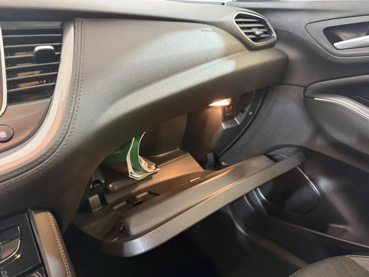 Vue intérieure côté passager de l'Opel Grandland X 2021, boîte à gants ouverte avec éclairage intérieur noir.