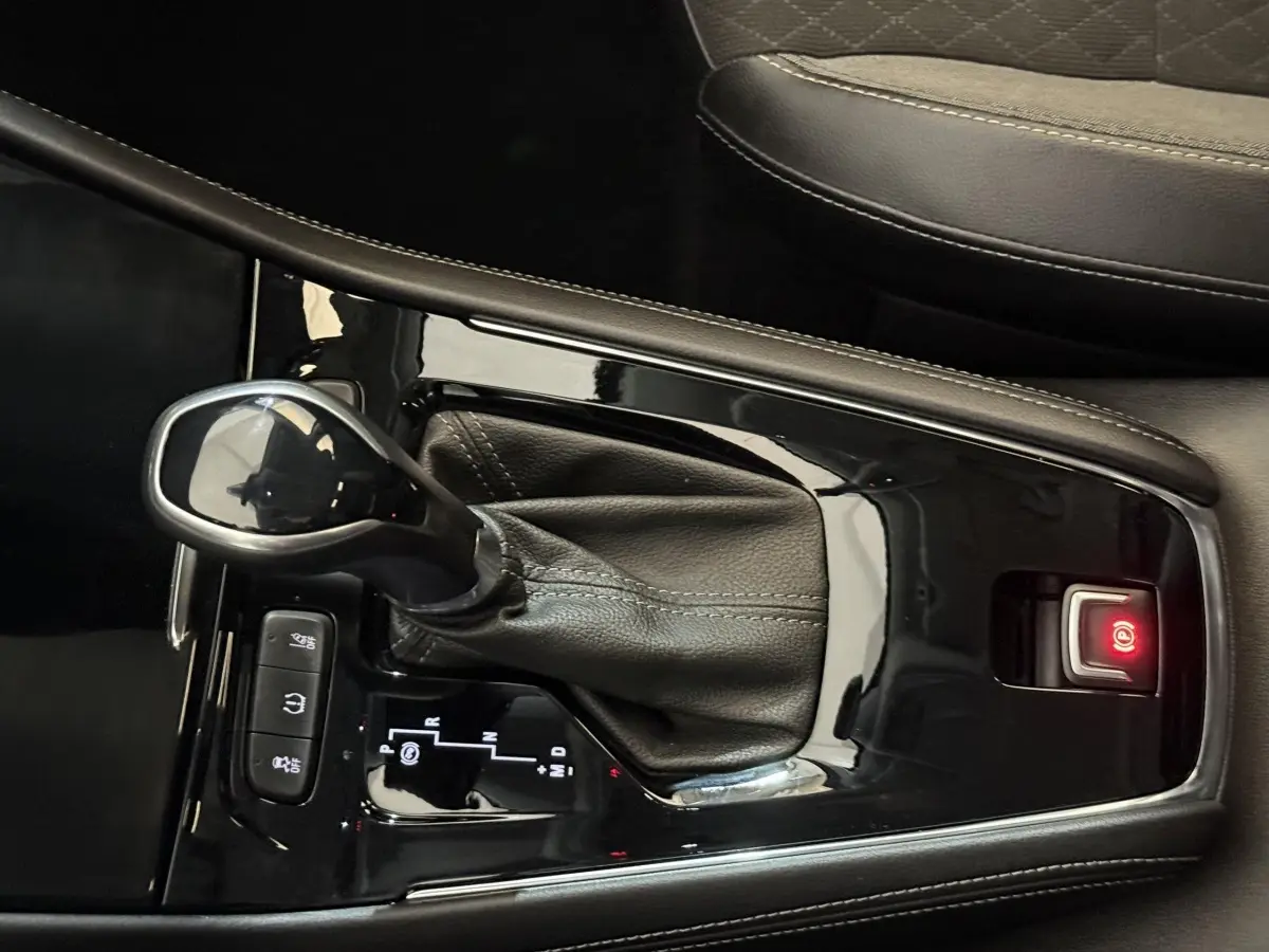 Gros plan sur la console centrale noire de l’Opel Grandland X 1.5 Diesel 130 Elegance Business Auto avec levier de vitesse automatique.