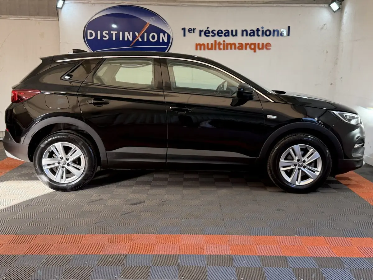 Opel Grandland X noir vue de profil côté gauche, avec jantes alliage et logo Distinxion en arrière-plan.