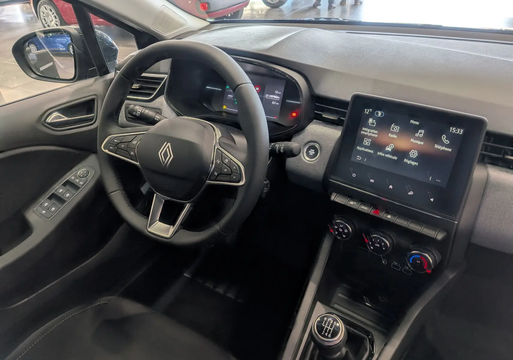 Vue intérieure côté conducteur de la Renault Clio V Bleu Iron, avec volant multifonction, écran tactile et boîte manuelle six vitesses.