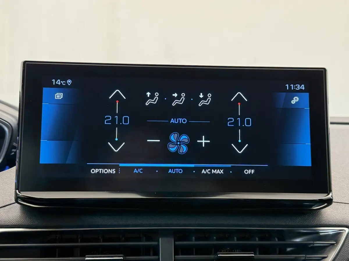 Écran tactile central affichant la climatisation bi-zone à 21°C dans un Peugeot 3008 gris foncé, vue intérieure frontale.