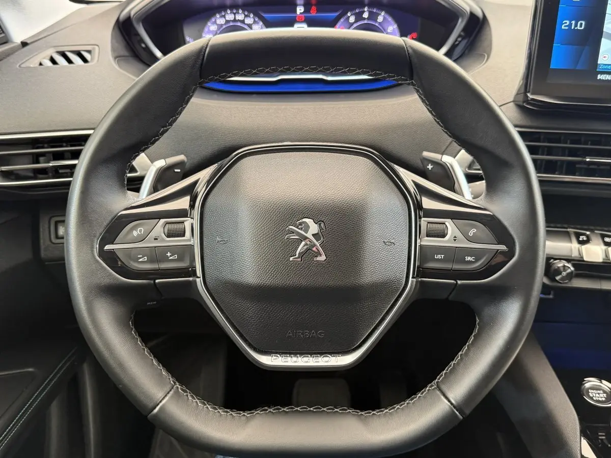 Vue rapprochée du volant cuir noir du Peugeot 3008 2022 avec commandes multifonctions et tableau de bord digital.