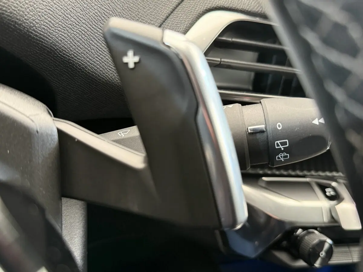 Gros plan sur la palette de changement de vitesse + côté gauche du volant du Peugeot 3008 gris foncé, intérieur moderne.