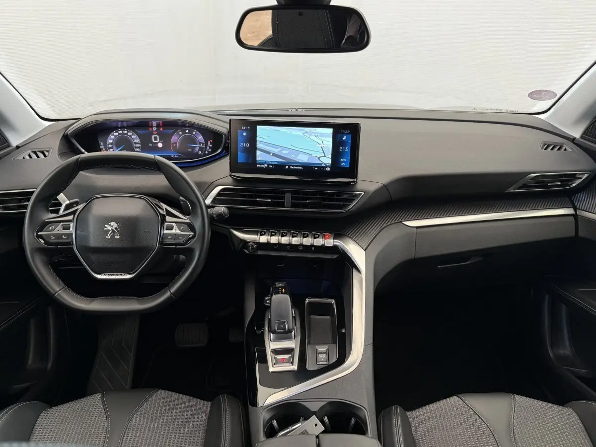 Vue intérieure avant du Peugeot 3008 gris foncé, tableau de bord avec écran tactile et volant cuir multifonctions.