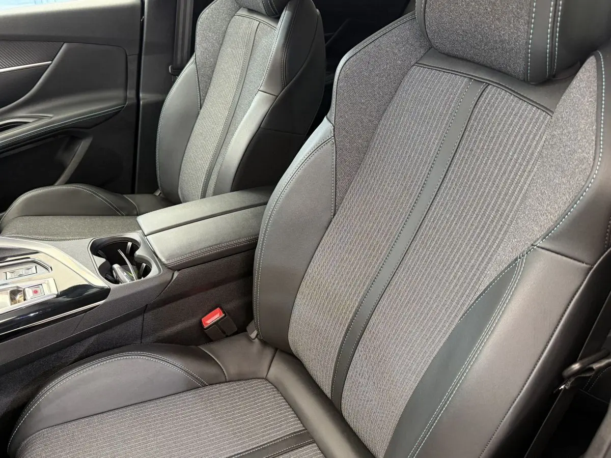 Gros plan sur les sièges avant gris cuir et tissu du Peugeot 3008 PureTech 130 Allure avec console centrale et accoudoir.