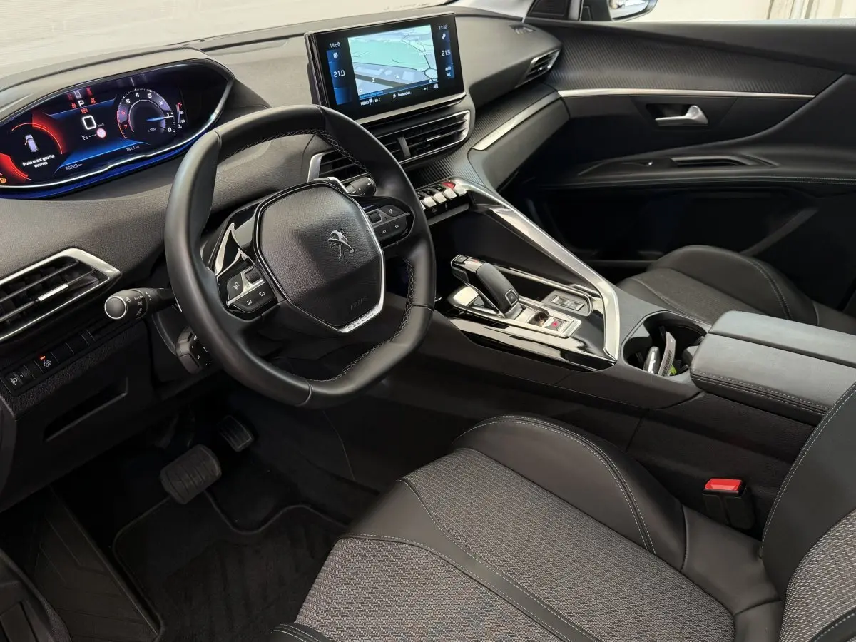 Intérieur avant droit du Peugeot 3008 gris foncé 2022, volant cuir, écran tactile et tableau de bord numérique.