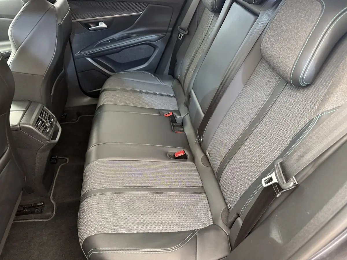Vue intérieure des sièges arrière du Peugeot 3008 gris foncé, montrant la banquette mixte tissu et cuir avec ceintures et appuie-têtes.