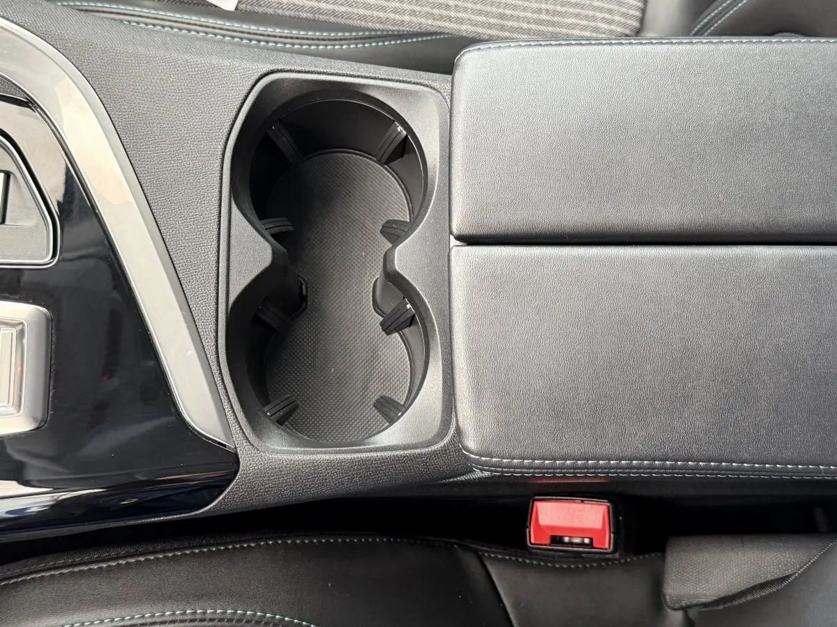 Gros plan sur la console centrale noire avec porte-gobelets et accoudoir cuir du Peugeot 3008 gris foncé 2022.