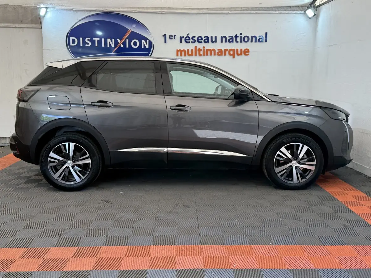 Vue de profil côté gauche du Peugeot 3008 gris foncé 2022 dans un showroom avec sol à damiers gris et orange.