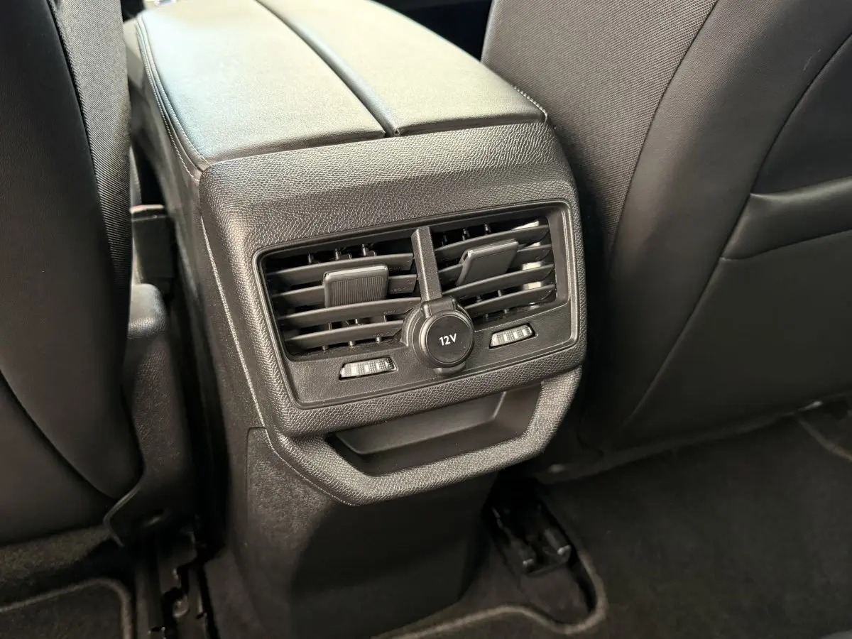 Détail des aérateurs arrière et prise 12V noirs sur la console centrale entre les sièges arrière d’un Peugeot 3008 gris foncé.