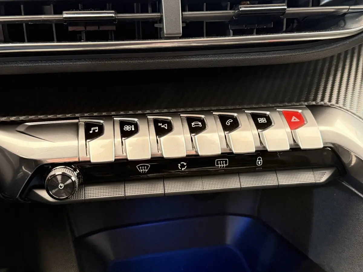 Gros plan sur la rangée de boutons chromés du tableau de bord du Peugeot 3008 gris foncé, 2022, version Allure.