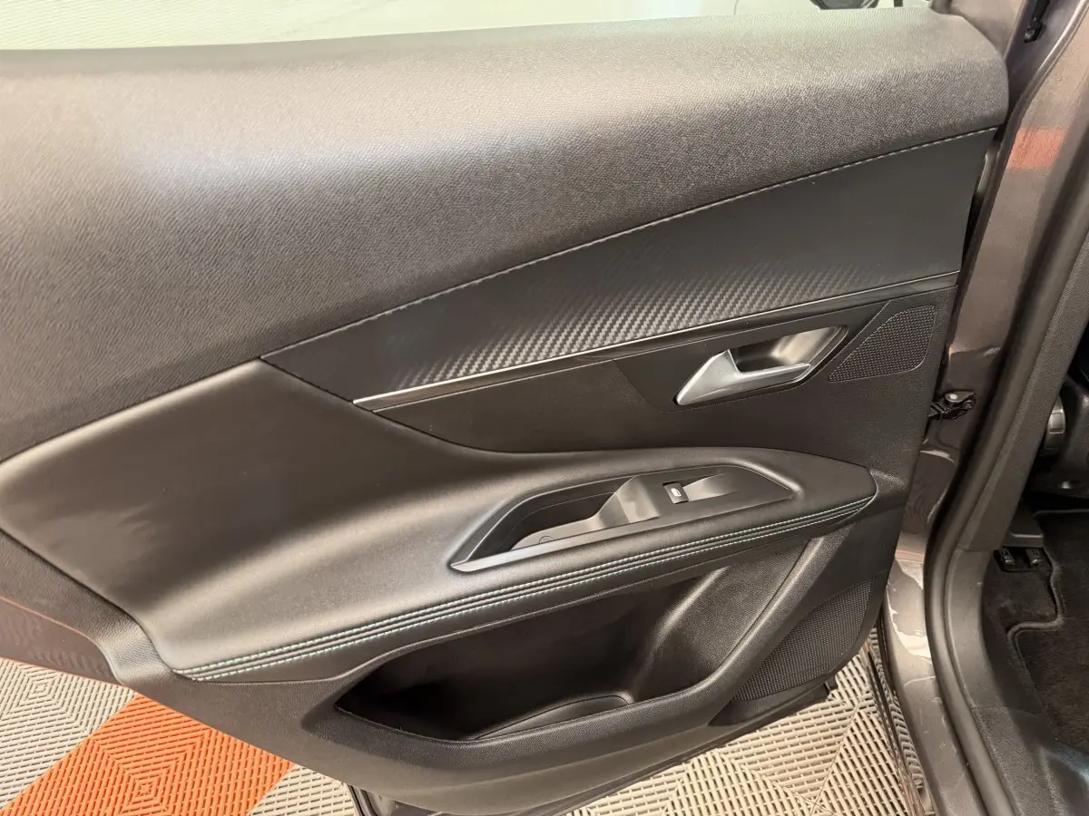 Vue rapprochée de la porte avant droite du Peugeot 3008 gris foncé, avec garniture noire et commandes de vitre.