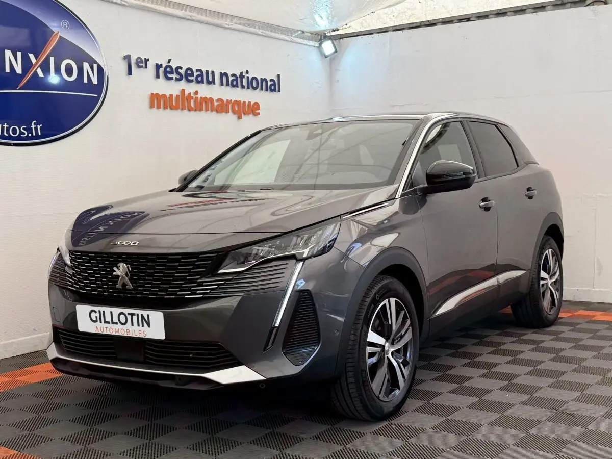 Peugeot 3008 gris foncé en 3/4 avant droit, avec calandre noire et feux LED distinctifs, en intérieur showroom.
