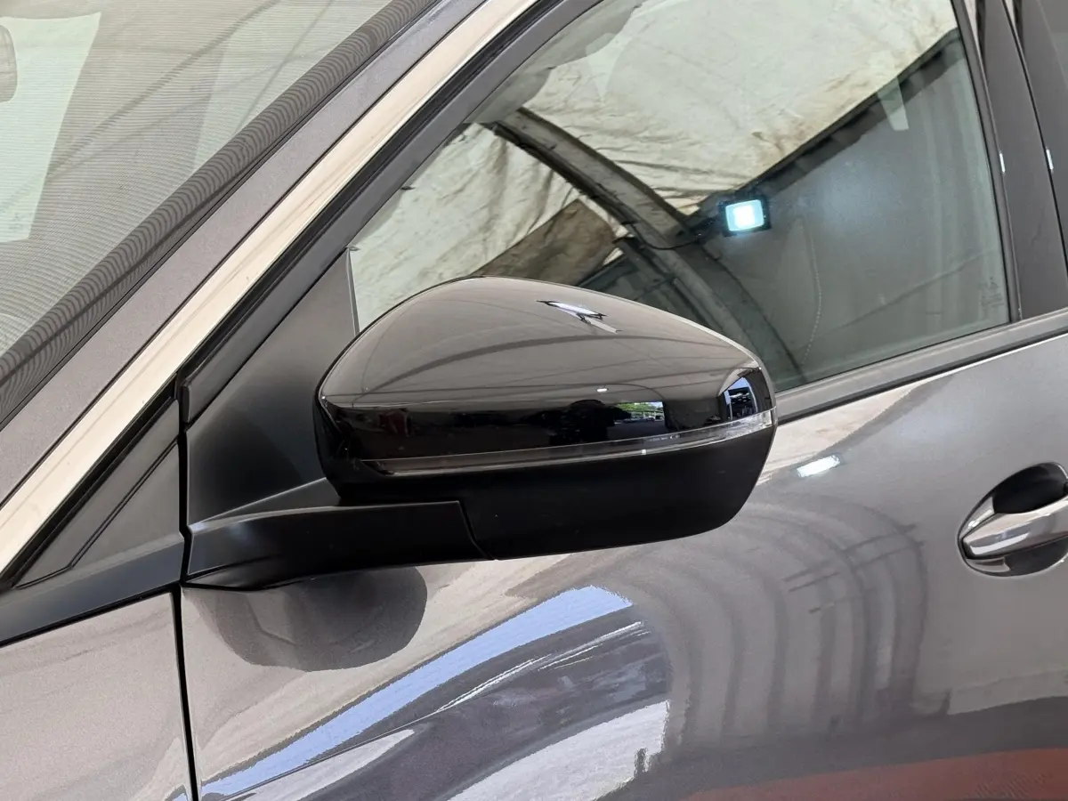 Gros plan sur le rétroviseur droit noir brillant d’un Peugeot 3008 gris foncé, avec la portière visible en arrière-plan.