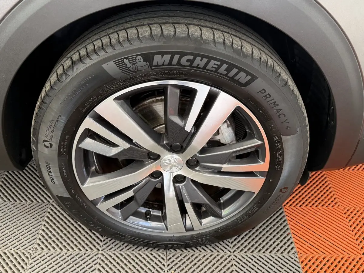 Gros plan sur la roue avant droite du Peugeot 3008 gris foncé, avec jante alliage et pneu Michelin Primacy 4.