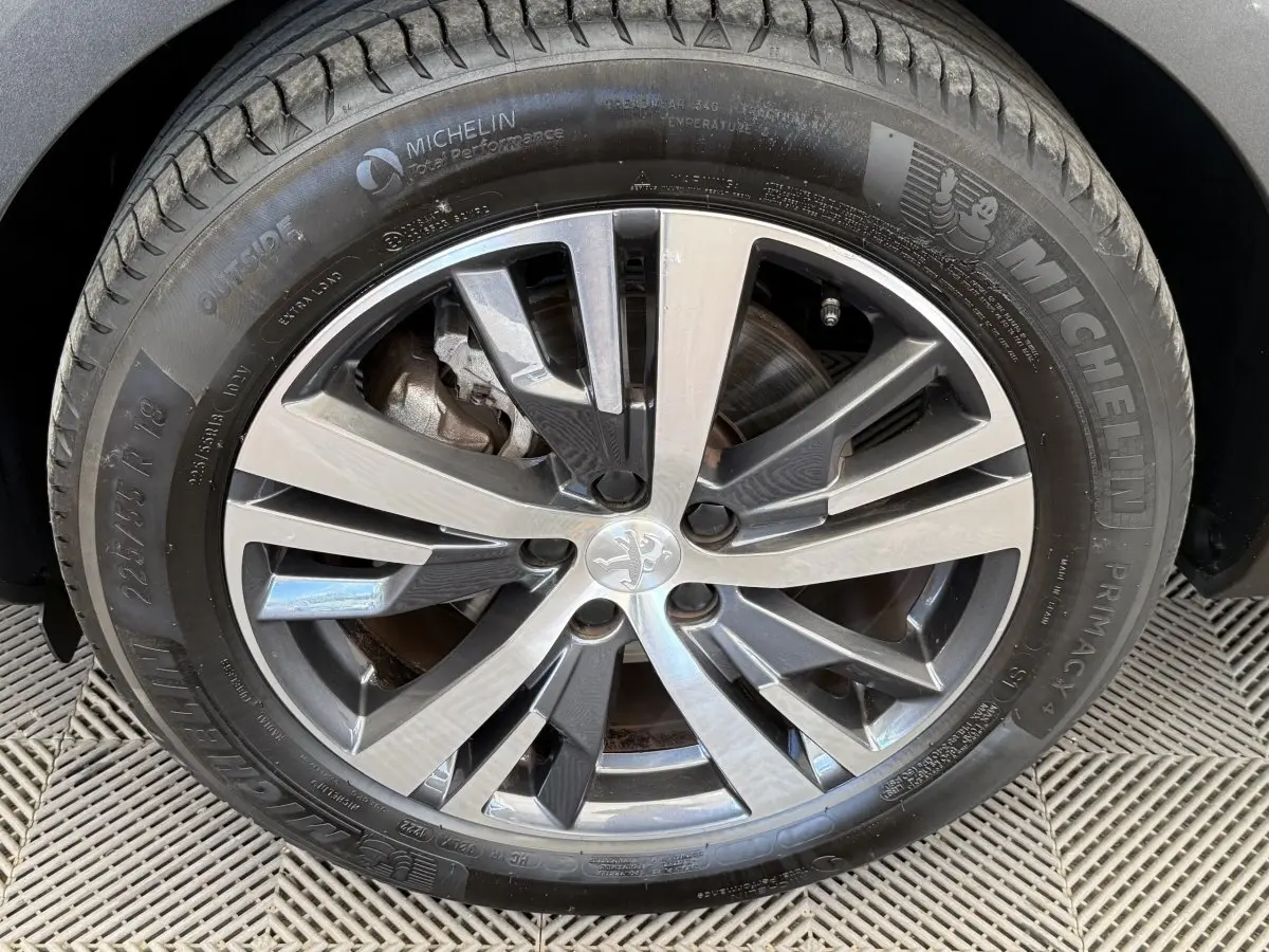 Gros plan sur la jante alliage 18 pouces et pneu Michelin d’un Peugeot 3008 gris foncé, version PureTech 130 Allure.