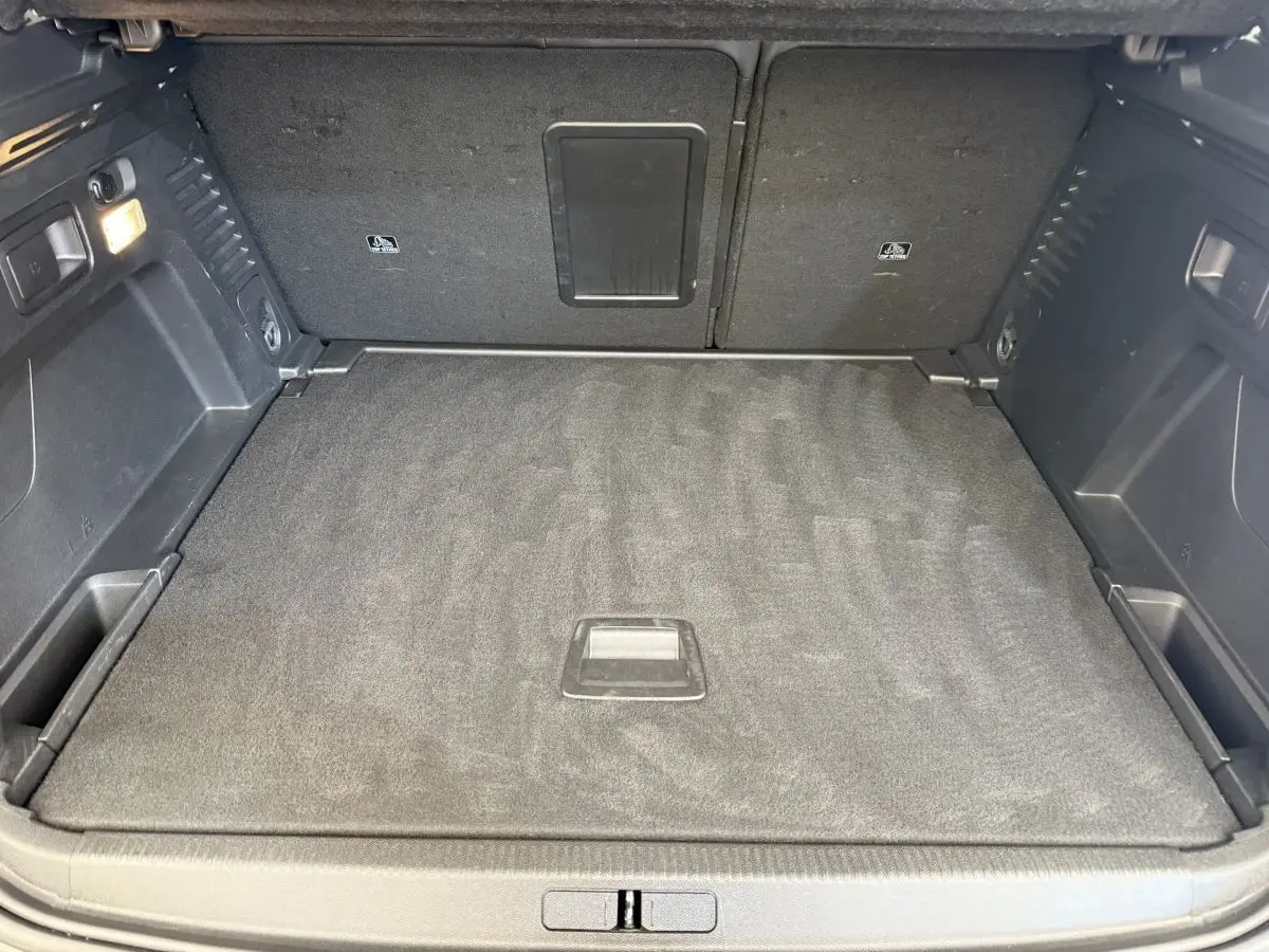 Vue intérieure du coffre spacieux et propre du Peugeot 3008 gris foncé, avec plancher plat et éclairage latéral.