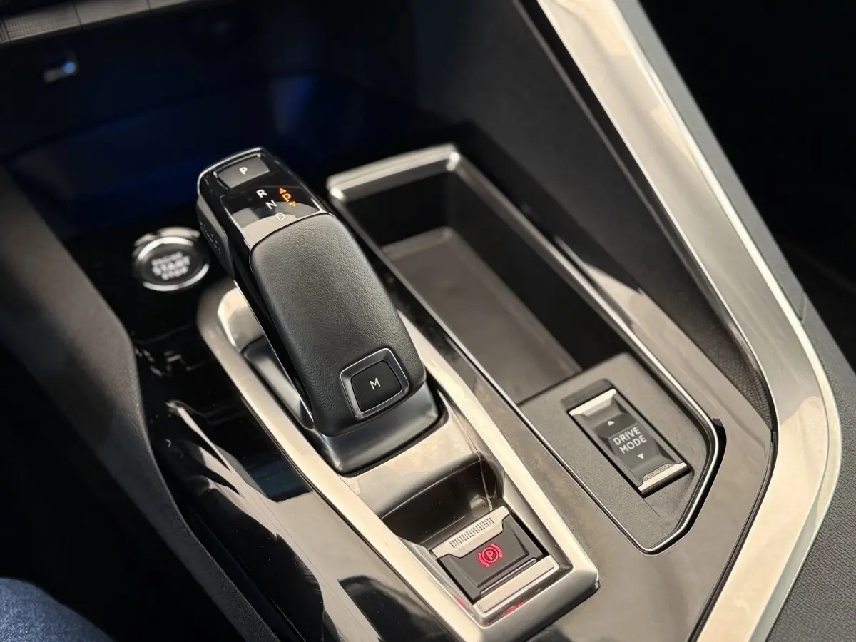 Gros plan sur la console centrale du Peugeot 3008 gris foncé, mettant en valeur le levier de vitesses automatique et le bouton Drive Mode.