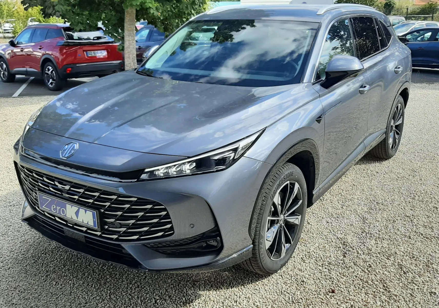 MG Motor EHS 1.5 Hybrid+ 224ch Luxury en Camden Grey, vue 3/4 avant droit avec calandre large et jantes bi-ton.