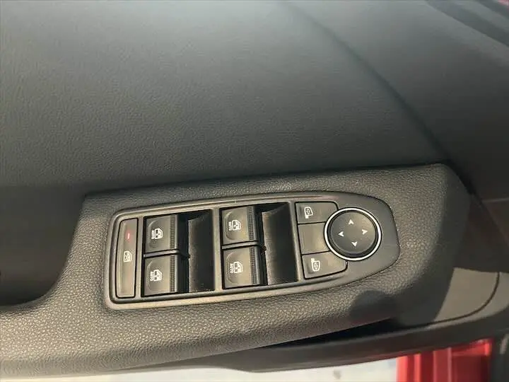 Panneau de commandes des vitres et rétroviseurs côté conducteur d'une Renault Clio V rouge flamme métal, vue intérieure rapprochée.