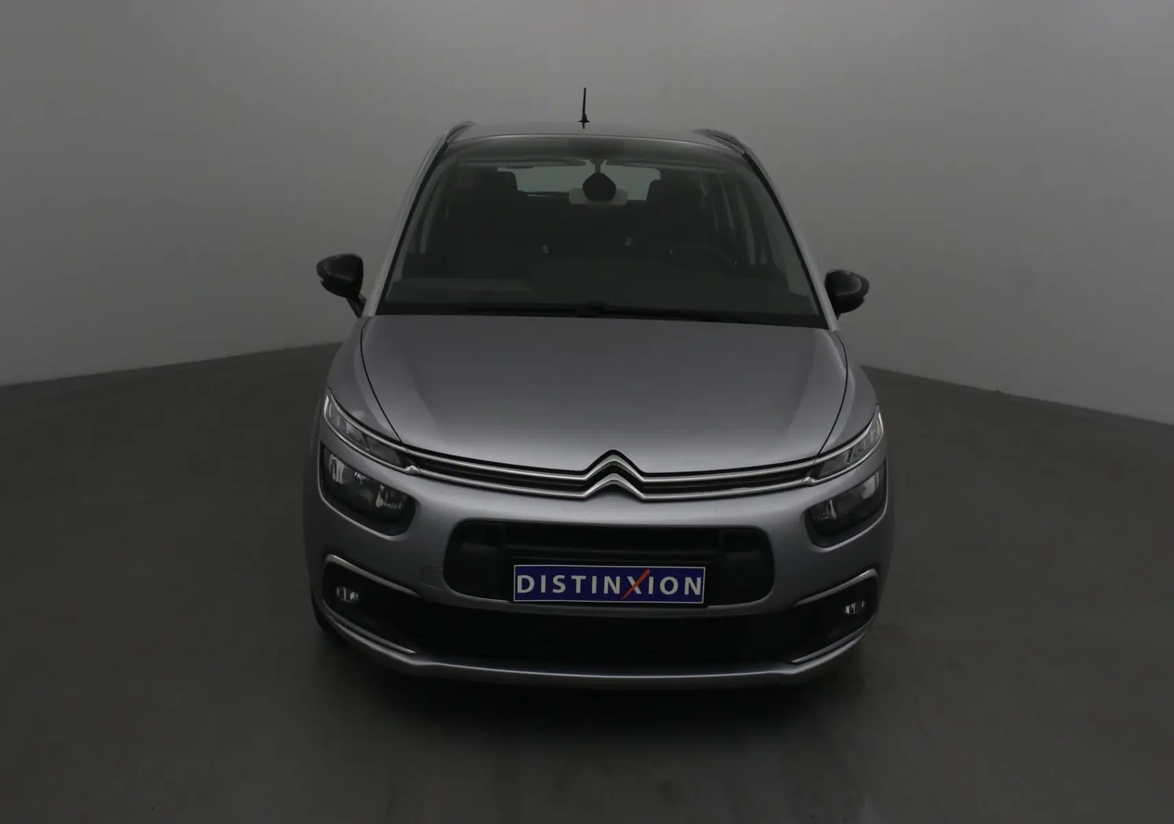 Vue frontale d'un Citroën Grand C4 Spacetourer gris Artense avec calandre distinctive et plaque Distinxion.