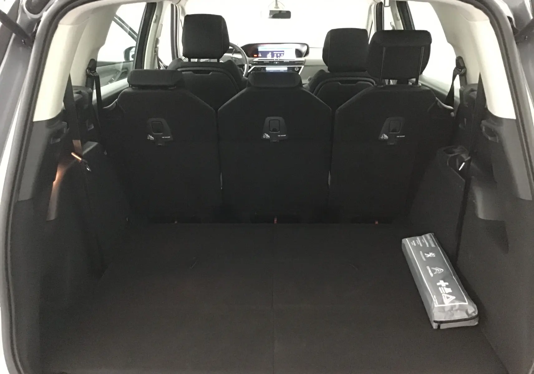 Coffre spacieux du Citroën Grand C4 Spacetourer gris Artense vu de l'arrière, avec sièges arrière relevés et kit de sécurité.