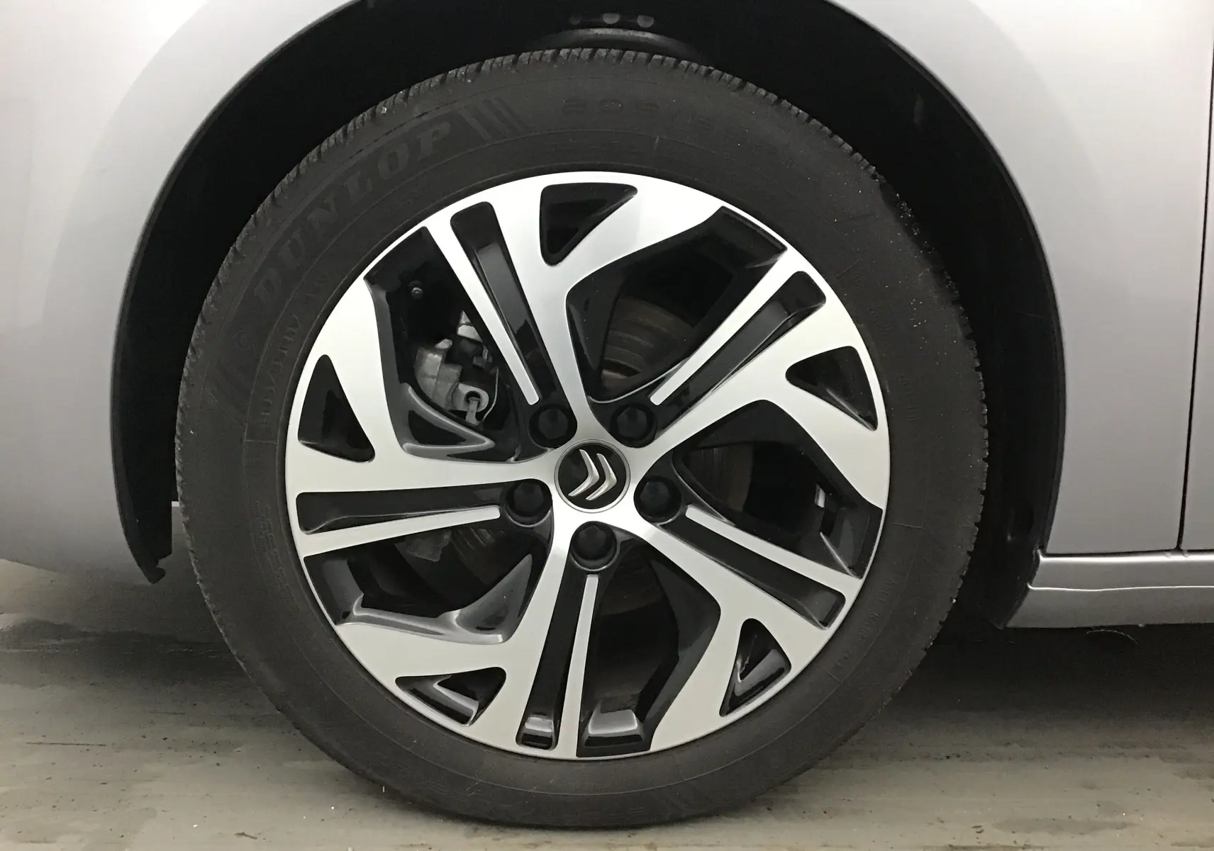 Gros plan sur la roue avant droite d'une Citroën Grand C4 Spacetourer gris Artense avec jante alliage bicolore.