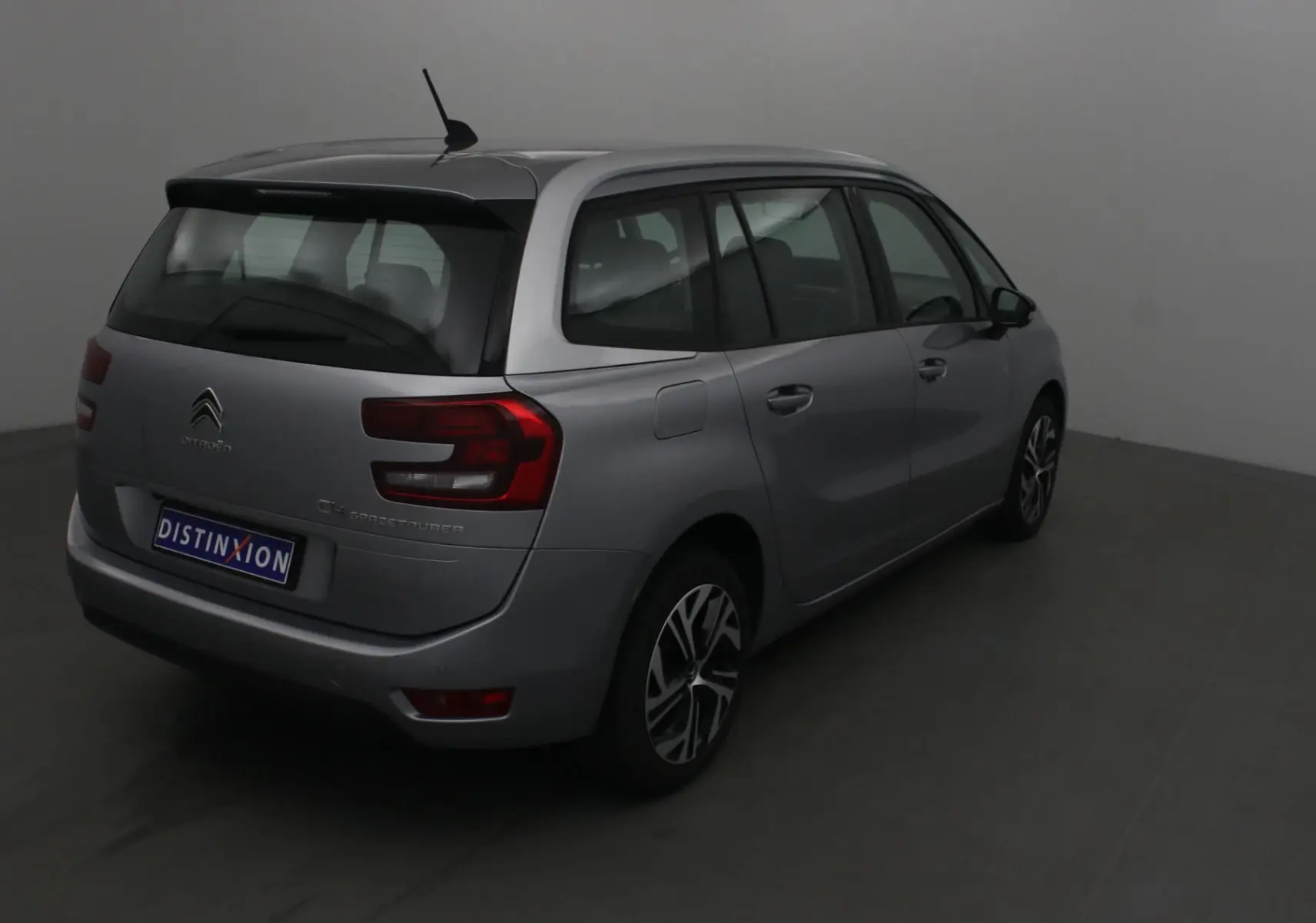 Citroën Grand C4 Spacetourer gris Artense vu de trois quarts arrière droit en intérieur neutre.