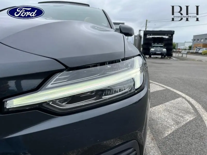 Gros plan sur le phare avant droit d'une Volvo V60 T8 gris Savile métallisé, soulignant son design LED moderne.